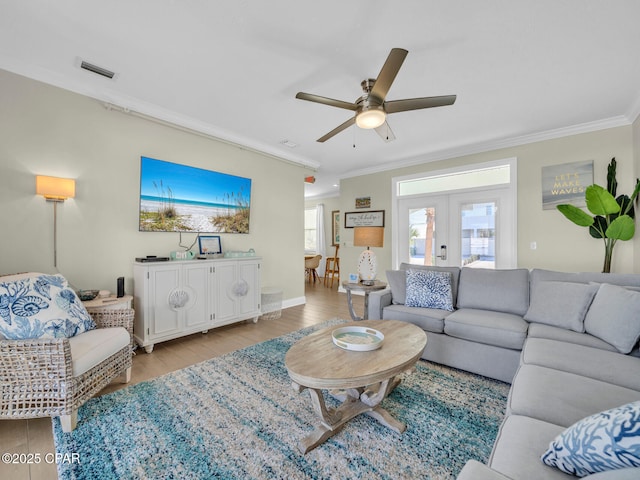 living room with visible vents, a ceiling fan, french doors, ornamental molding, and light wood finished floors