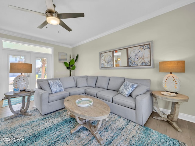 living room featuring a ceiling fan, baseboards, crown molding, and wood finished floors