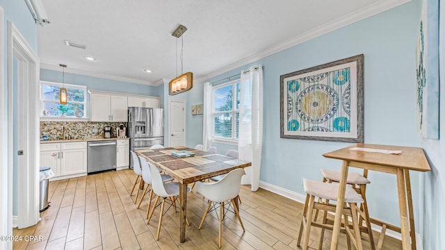 dining area featuring ornamental molding, light hardwood / wood-style floors, and sink