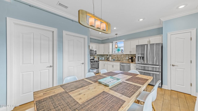 kitchen featuring light hardwood / wood-style flooring, stainless steel appliances, white cabinetry, and hanging light fixtures