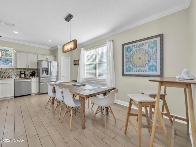 dining space with baseboards, light wood finished floors, recessed lighting, and crown molding