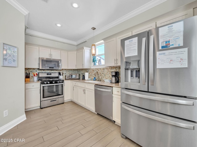 kitchen with appliances with stainless steel finishes, light wood-style floors, crown molding, and backsplash