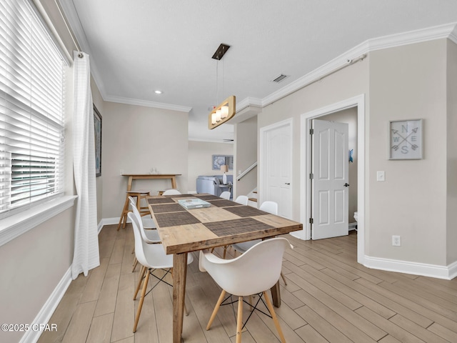 dining area with ornamental molding, visible vents, light wood-style flooring, and baseboards