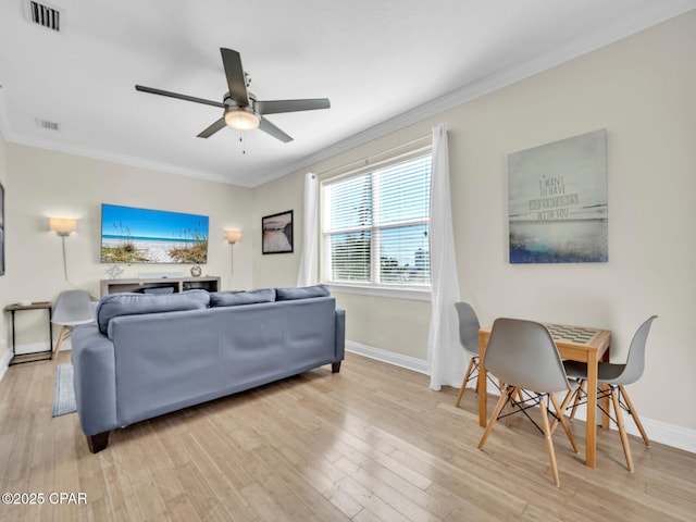 living area featuring crown molding, baseboards, visible vents, and light wood-style floors