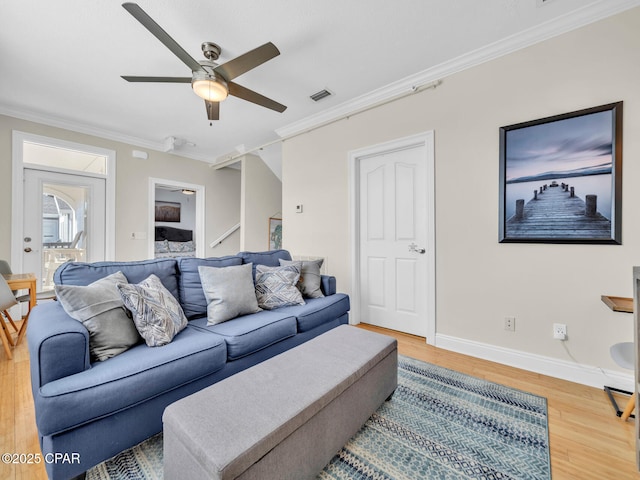 living area featuring baseboards, visible vents, ceiling fan, wood finished floors, and crown molding