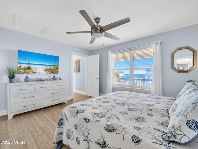 bedroom featuring baseboards, ceiling fan, attic access, and light wood-style floors