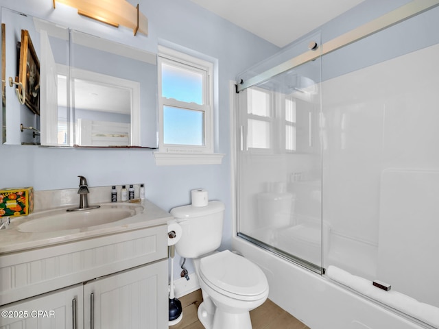 full bath with combined bath / shower with glass door, vanity, and toilet