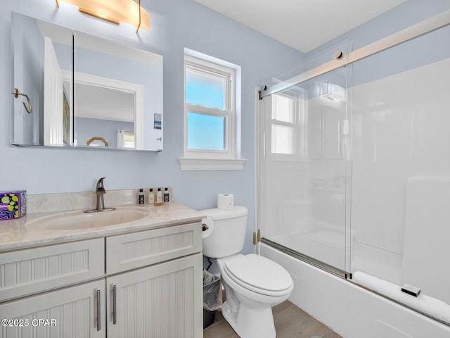 bathroom with vanity, toilet, and bath / shower combo with glass door