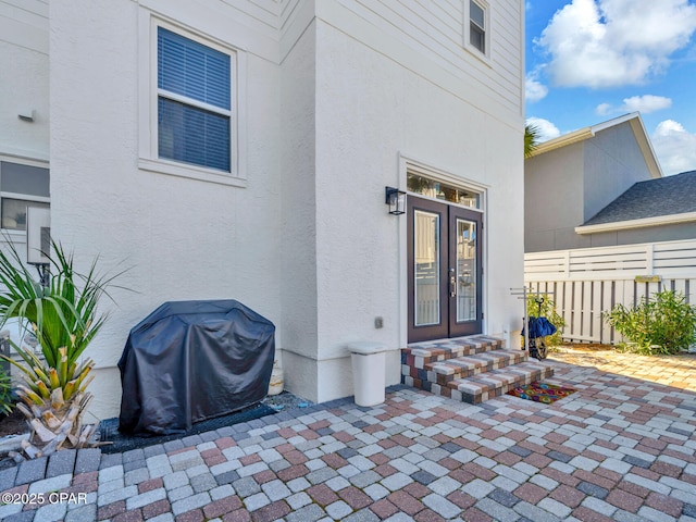 doorway to property with a patio, fence, french doors, and stucco siding