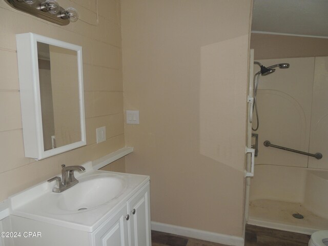 bathroom with vanity, toilet, hardwood / wood-style flooring, and a shower