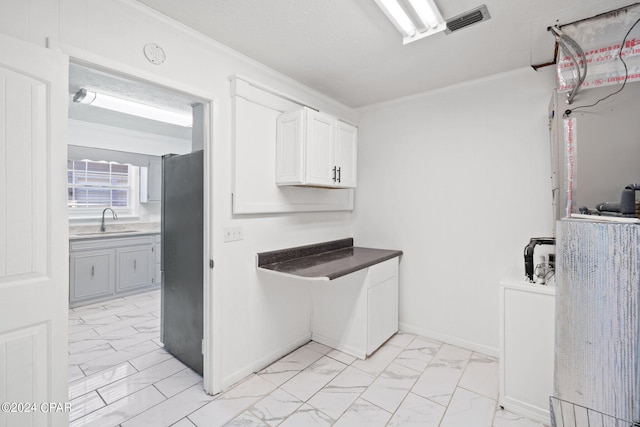 kitchen featuring sink, light tile patterned flooring, ornamental molding, and white cabinetry