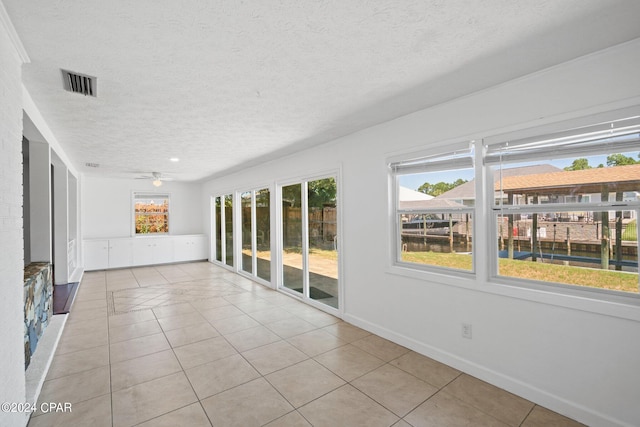 empty room with ceiling fan, a textured ceiling, and light tile patterned floors