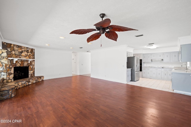 unfurnished living room with a fireplace, ornamental molding, a textured ceiling, and light tile patterned floors