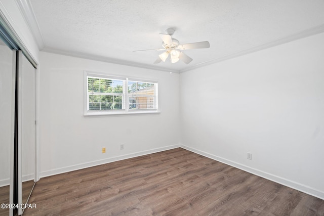 unfurnished bedroom featuring dark wood-type flooring, a closet, a textured ceiling, ceiling fan, and crown molding