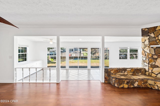 interior space featuring tile patterned flooring, ceiling fan, a textured ceiling, and crown molding