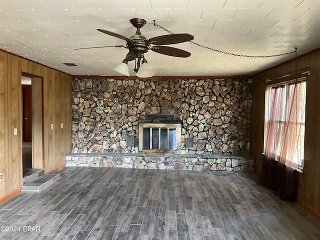 unfurnished living room featuring a wealth of natural light, a fireplace, wood walls, and wood-type flooring