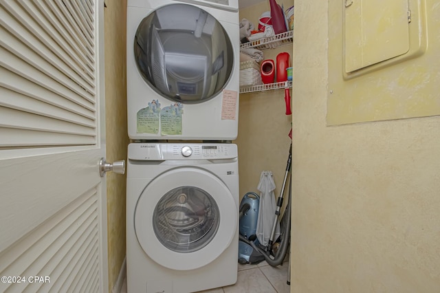 washroom with stacked washer and clothes dryer, electric panel, and light tile patterned floors