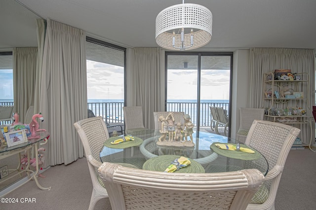 carpeted dining space with a wall of windows, a chandelier, and a water view