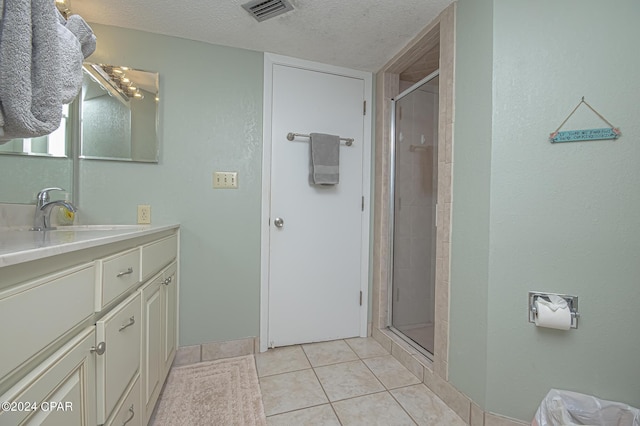 bathroom featuring vanity, a shower with door, tile patterned floors, and a textured ceiling