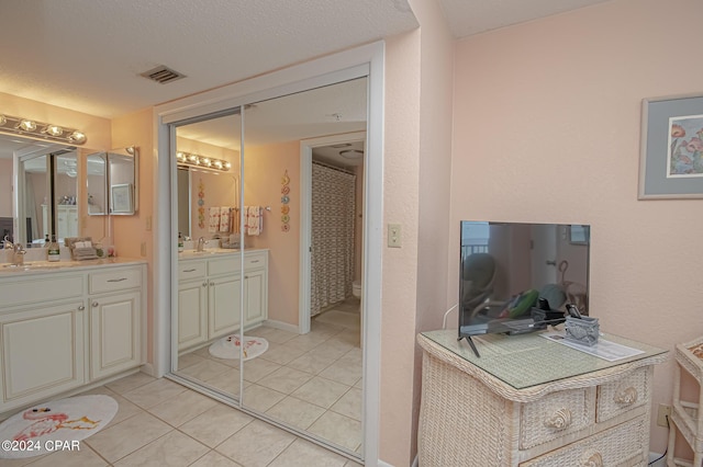 bathroom with tile patterned floors, vanity, and a textured ceiling