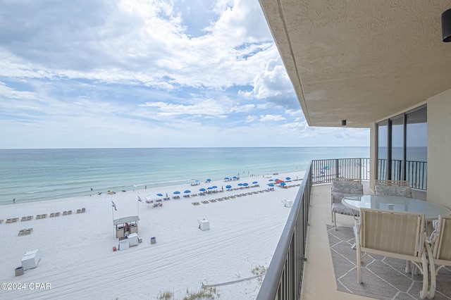 balcony featuring a view of the beach and a water view