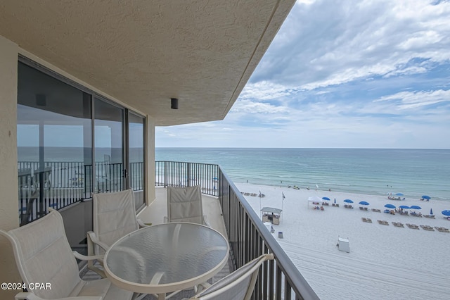 balcony featuring a view of the beach and a water view