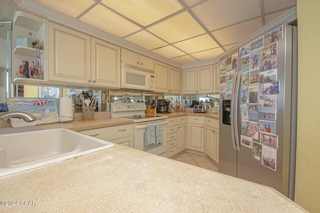 kitchen featuring cream cabinets, light tile patterned floors, stainless steel appliances, sink, and a paneled ceiling