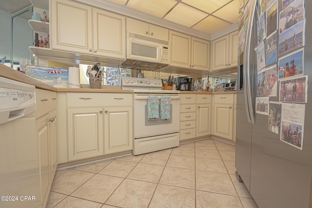 kitchen with light tile patterned floors, white appliances, and cream cabinetry