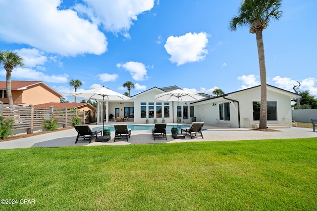 back of house featuring a yard, a fenced in pool, and a patio area