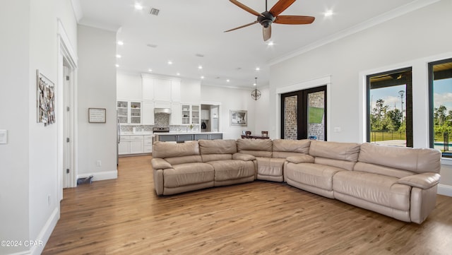 living room with ornamental molding, ceiling fan, and light hardwood / wood-style flooring