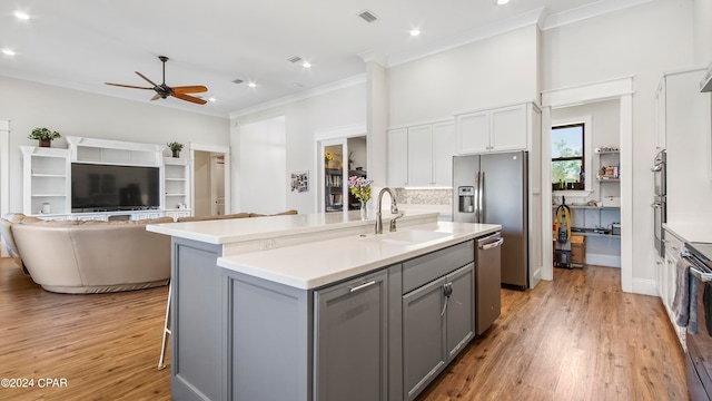 kitchen featuring sink, light hardwood / wood-style flooring, stainless steel appliances, a center island with sink, and ceiling fan