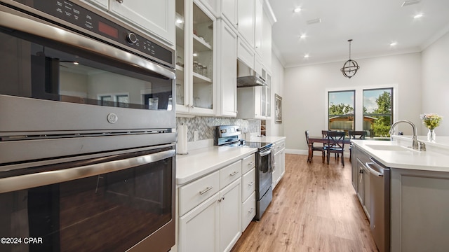 kitchen featuring stainless steel appliances, white cabinets, hanging light fixtures, and sink