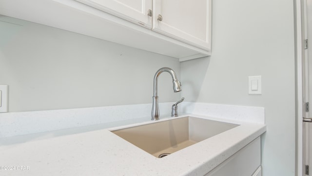 interior space featuring white cabinetry, light stone counters, and sink