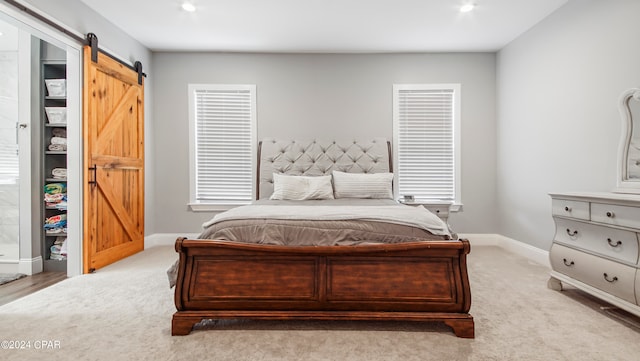 carpeted bedroom featuring a barn door