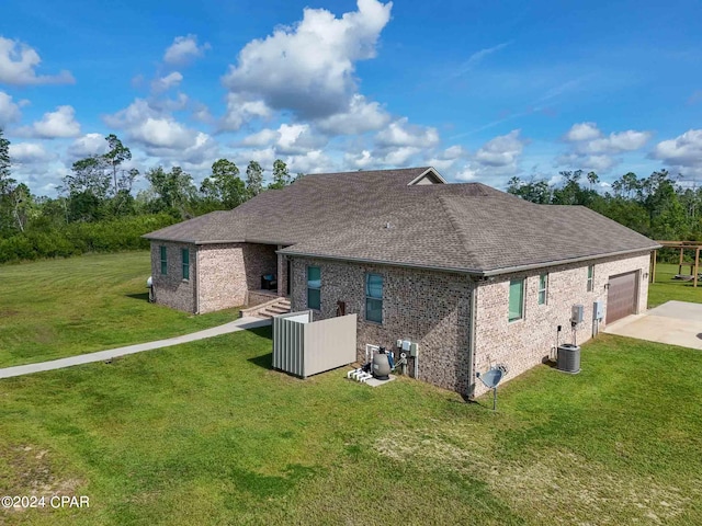 back of property with a garage, a yard, and central AC