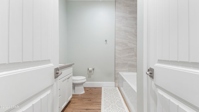 bathroom with vanity, toilet, a washtub, and hardwood / wood-style flooring