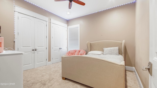 carpeted bedroom featuring ceiling fan and multiple closets