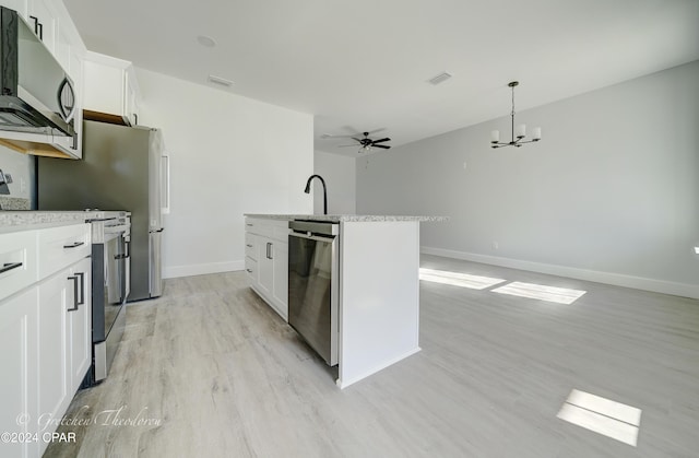 kitchen featuring stainless steel appliances, white cabinetry, a center island with sink, and pendant lighting