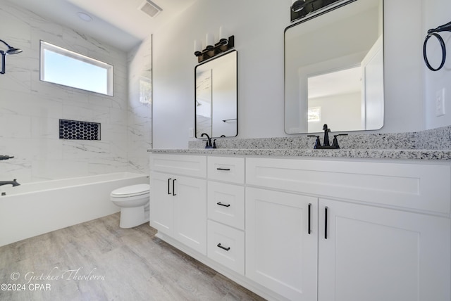 full bathroom featuring hardwood / wood-style flooring, vanity, tiled shower / bath, and toilet