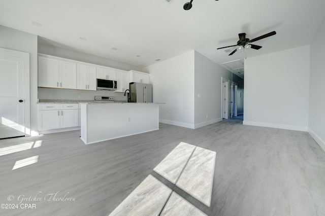 kitchen with light stone counters, an island with sink, stainless steel appliances, light hardwood / wood-style floors, and white cabinets