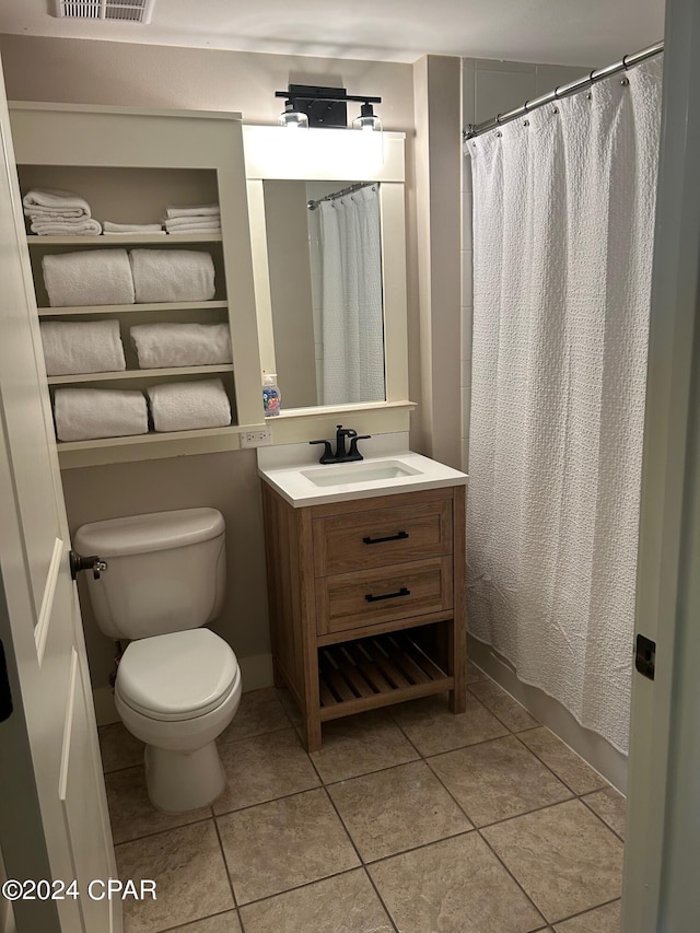 bathroom with a shower with curtain, vanity, toilet, and tile patterned floors