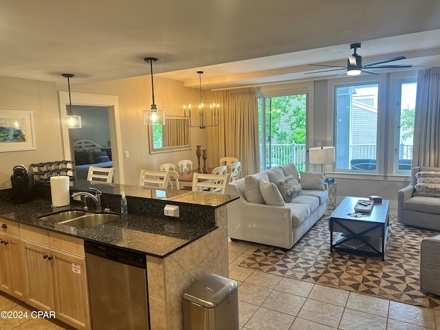 kitchen with ceiling fan with notable chandelier, dishwasher, decorative light fixtures, a center island with sink, and sink