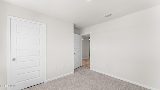 unfurnished bedroom featuring light carpet and a closet