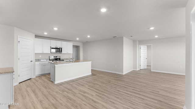 kitchen featuring sink, stainless steel appliances, an island with sink, light hardwood / wood-style floors, and white cabinets