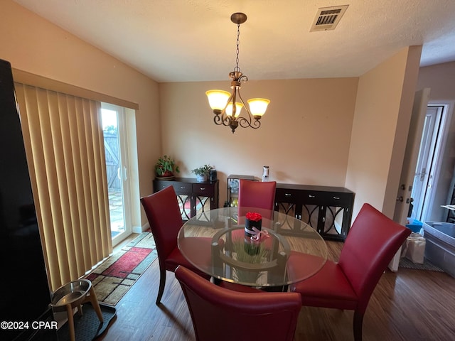 dining area featuring hardwood / wood-style floors, a notable chandelier, and a textured ceiling