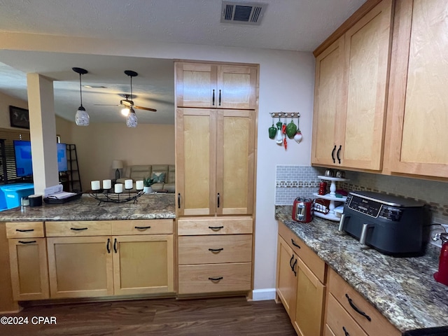 kitchen with dark hardwood / wood-style flooring, dark stone countertops, backsplash, light brown cabinets, and ceiling fan