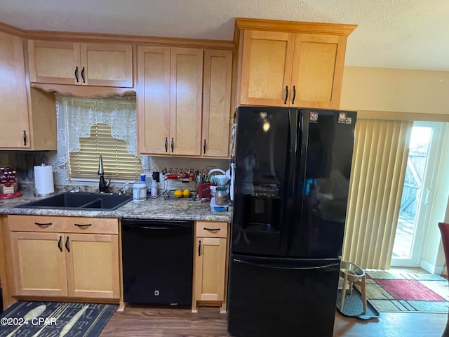 kitchen featuring plenty of natural light, black appliances, sink, and light stone countertops