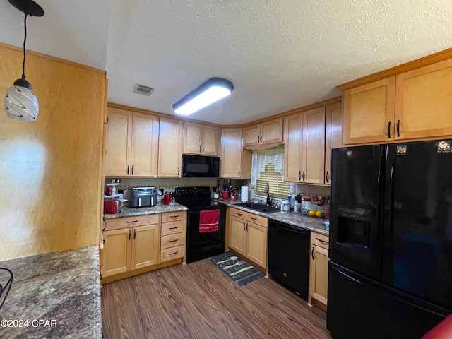 kitchen with decorative light fixtures, sink, black appliances, dark stone counters, and dark wood-type flooring