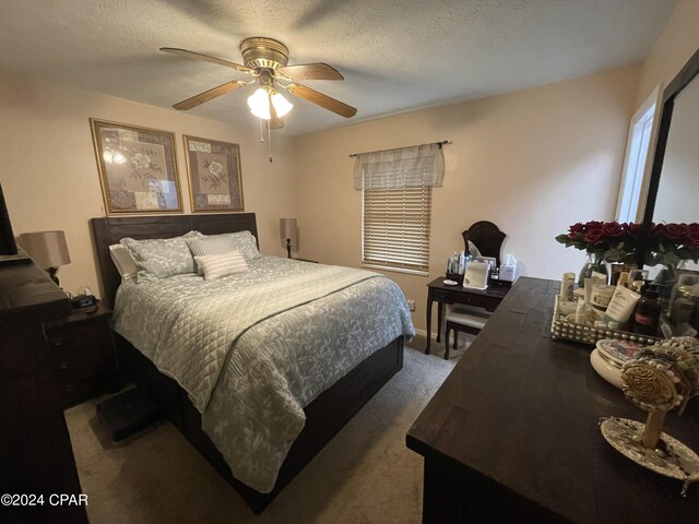 carpeted bedroom with ceiling fan and a textured ceiling