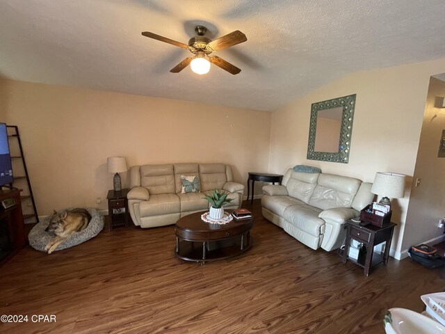 living room featuring ceiling fan, dark hardwood / wood-style floors, vaulted ceiling, and a textured ceiling